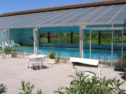 - un pavillon avec une table et des chaises à côté de la piscine dans l'établissement Logis Hôtel Relais Paris Bale - Restaurant La Mangeoire, à Montieramey