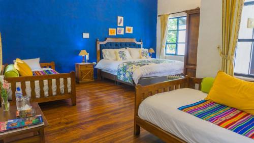 a blue room with two beds and a couch at Hostería Hacienda Pinsaqui in Otavalo