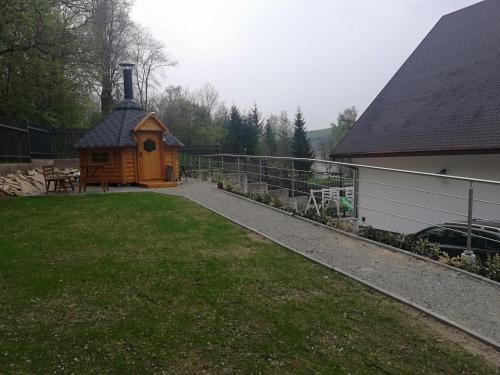 a small cabin in a yard next to a house at Pokoje Na Szlaku in Lądek-Zdrój