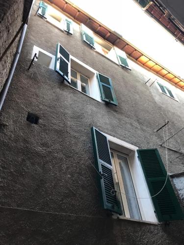 un edificio con puertas verdes y ventanas. en A’ ca’ de Giuli’, en Badalucco