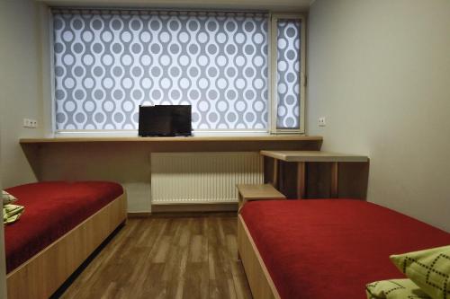 a room with two beds and a window with a tv at Hostel Laurita in Kaunas