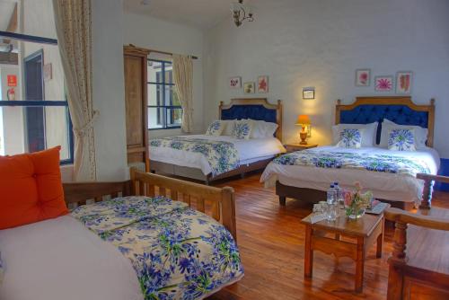 a hotel room with three beds and a table at Hostería Hacienda Pinsaqui in Otavalo