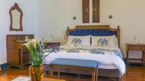 a bedroom with a bed and a vase with flowers at Hostería Hacienda Pinsaqui in Otavalo