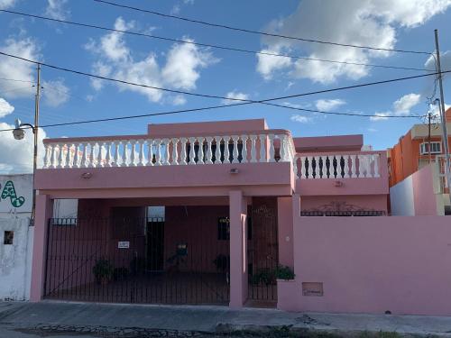a pink building with a balcony on top of it at casa alegria in Mérida