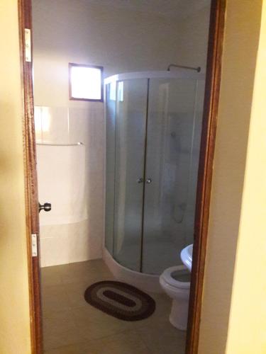 a bathroom with a glass shower and a toilet at Casa Alegre in São Filipe