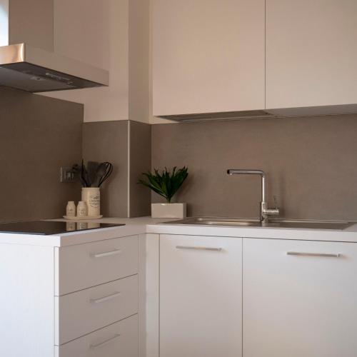 a kitchen with white cabinets and a sink at La Casa Verde - Apartment in Lasino