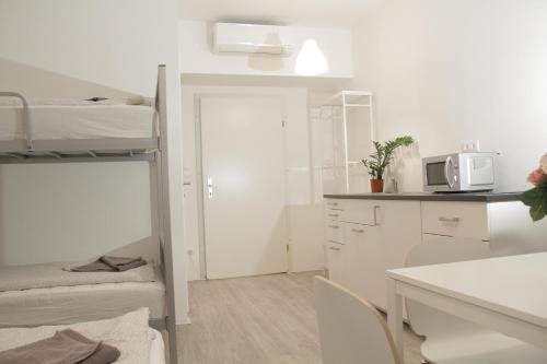 a small white room with a kitchen and bunk beds at Betariel Apartments S32 in Vienna