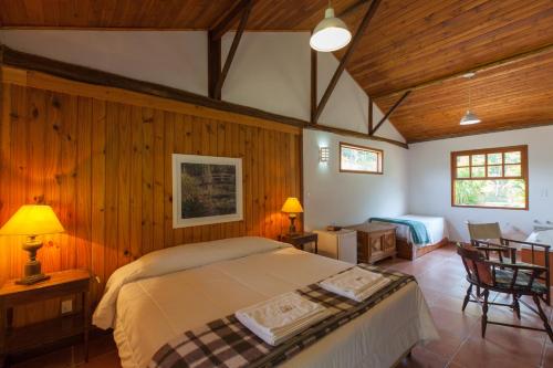 sypialnia z dużym łóżkiem w pokoju z drewnianymi ścianami w obiekcie Pousada Mariza w mieście Nova Friburgo