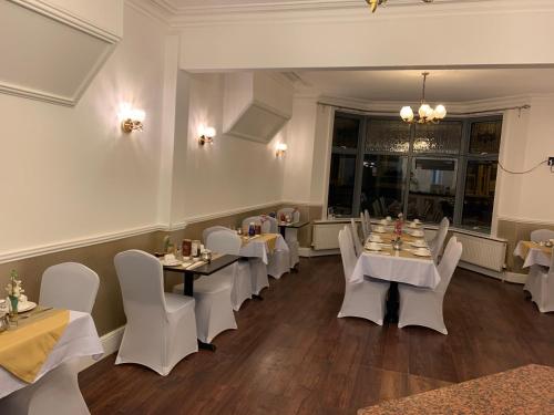 a dining room with white tables and white chairs at Swandown Hotel in Swindon