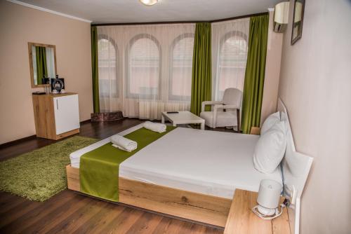 a bedroom with a large bed with green curtains at Hotel Oppium Restaurant & Garden in Ruse