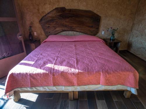 a bedroom with a large bed with a wooden headboard at Flor de Cera in Tepoztlán