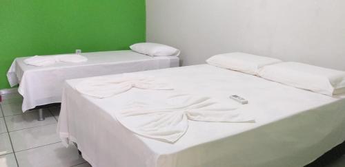 two beds in a room with a green wall at Estância Cyclo das Águas in Nobres