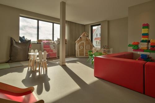 a living room with a red couch and a table at Hotel de Blanke Top in Cadzand-Bad