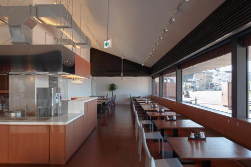 a restaurant with wooden tables and chairs and windows at Iseya, Seaview Private Oceanside Bath in Unzen