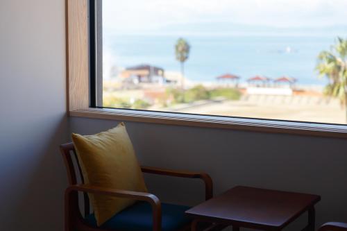 a chair with a pillow sitting next to a window at Iseya, Seaview Private Oceanside Bath in Unzen