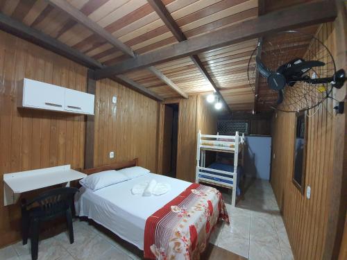 a bedroom with a bed and a desk and a fan at Residencial Rei Thomas in Capão da Canoa