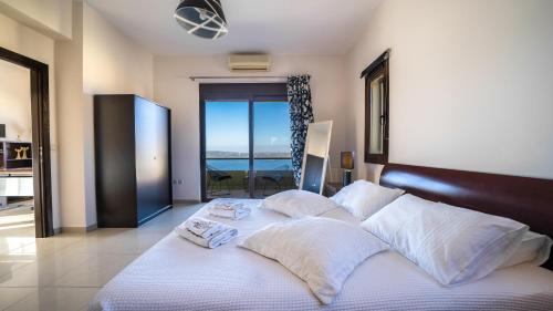 una camera da letto con un grande letto con lenzuola e cuscini bianchi di Villa Majestic Crete heated pool and sauna a Megála Khoráfia