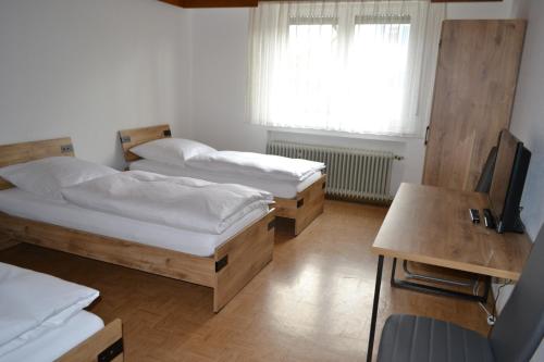 a room with two beds and a desk and a television at Ferienwohnung Krone in Sankt Johann