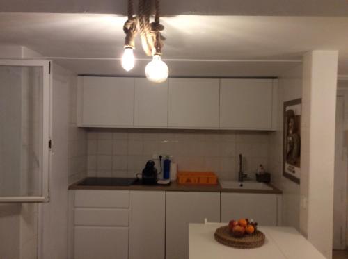 a kitchen with white cabinets and a bowl of fruit on a table at Bilocale vista mare Es Pujols in Es Pujols