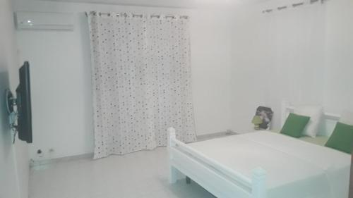 a white bedroom with a white bed and a curtain at Villa Paradis Ultime in Morne-à-lʼEau