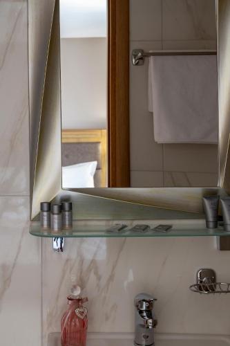 a bathroom with a mirror and a sink at Afroditi Hotel in Paralia Katerinis