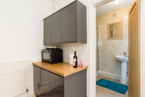 a kitchen with a counter with a microwave and a sink at Cosy Studio Flat in Newport