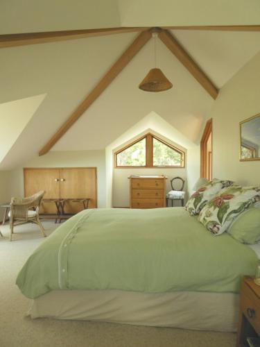 a bedroom with a green bed and a table at Waiwurrie Coastal Farm Lodge in Mahinepua