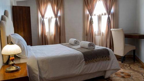 a bedroom with a bed and a table and two windows at Lunandina Huaraz in Huaraz