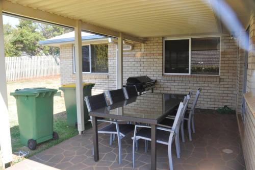 a patio with a table and chairs under a roof at Ridgehouse in Toowoomba