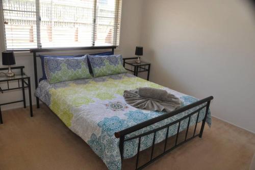 1 cama en un dormitorio con 2 mesas y una ventana en Ridgehouse en Toowoomba