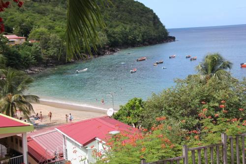 people on a beach with boats in the water at Résidence Séjourné in Les Anses-dʼArlets