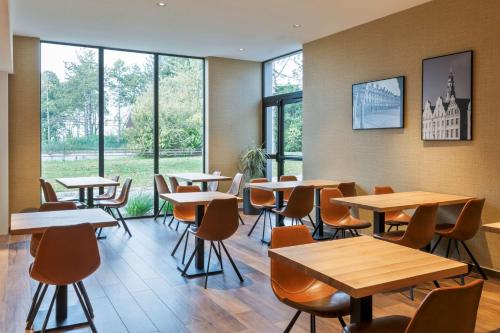 a restaurant with tables and chairs and windows at Best Western L'Aquarium Arras Nord in Fresnes-lès-Montauban