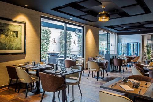 a restaurant with tables and chairs and windows at Best Western L'Aquarium Arras Nord in Fresnes-lès-Montauban