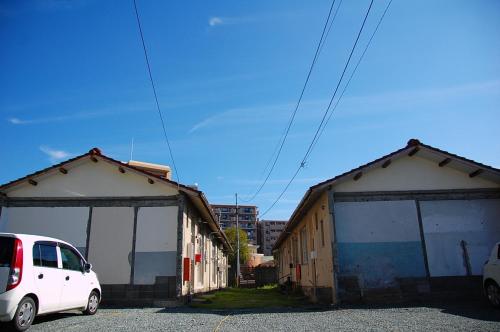 a white car parked in a parking lot between two buildings at OBI HOUSE B1母屋room in Shimo-tatsuda
