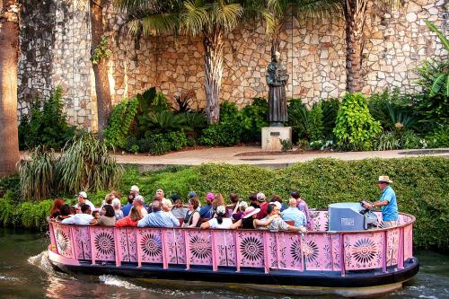 people riding on top of a boat on a river at O'Brien Riverwalk Boutique Hotel in San Antonio