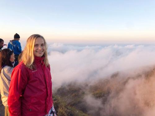a young girl standing on top of a mountain with clouds at Batur Pyramid Guesthouse in Kintamani