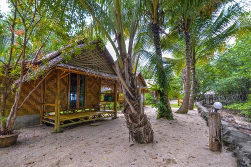 a wooden shack with a palm tree in front of it at Bananas Resort & Restaurant in Tha Lane Bay