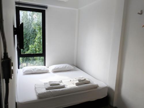 Schlafzimmer mit einem Bett mit weißer Bettwäsche und einem Fenster in der Unterkunft HOLY SHEET Hostel in Bangkok