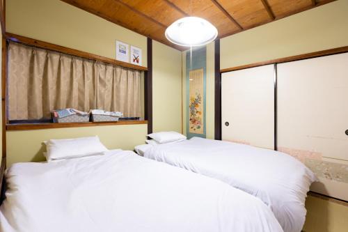 two white beds in a room with a window at Family house (private house) in Osaka