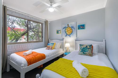 two beds in a room with a window at Family, Romance, Fun on Kings Beach in Caloundra