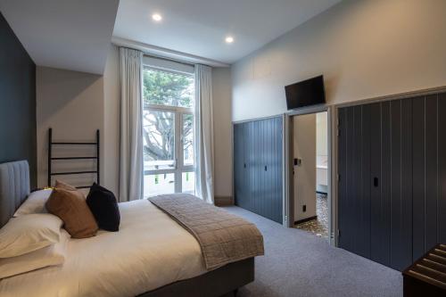 um quarto com uma cama grande e uma janela grande em The Burlington Luxury Octagon Apartment em Dunedin