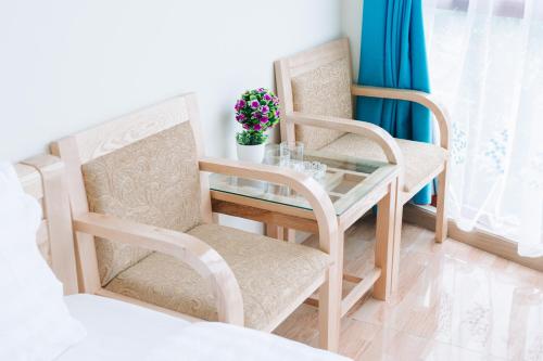 河內的住宿－La Teisu Airport Hotel，卧室配有两把椅子和一张玻璃桌