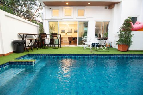 a house with a swimming pool with a table and chairs at Room@Gallery Pool Villa in Pattaya South