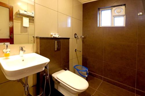 uma casa de banho com um lavatório, um WC e um espelho. em Hotel Wilton em Sultan Bathery