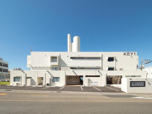 a white building with a key sign in front of it at SEAMORE RESIDENCE in Shirahama