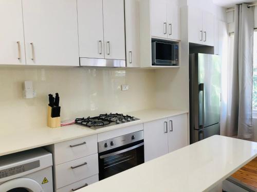 a kitchen with white cabinets and a stove top oven at Lotus Stay Manly - Apartment 31C in Sydney