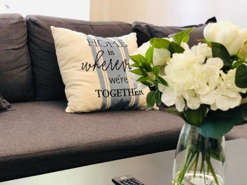 a vase of flowers on a table with a couch at Lotus Stay Manly - Apartment 31C in Sydney