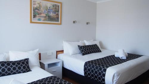 Habitación con 2 camas y una foto en la pared. en Queanbeyan Motel, en Queanbeyan