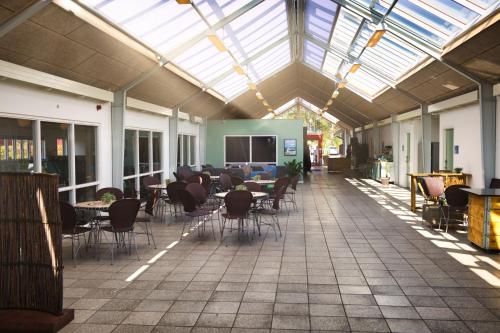 a cafeteria with tables and chairs and a glass ceiling at Danhostel Ishøj Strand in Ishøj