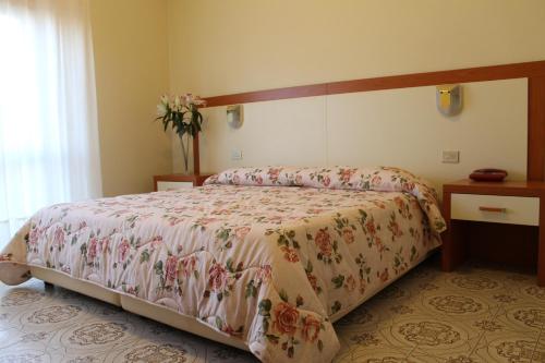 a bedroom with a bed with a floral bedspread at Hotel Ismaele in Chiusi